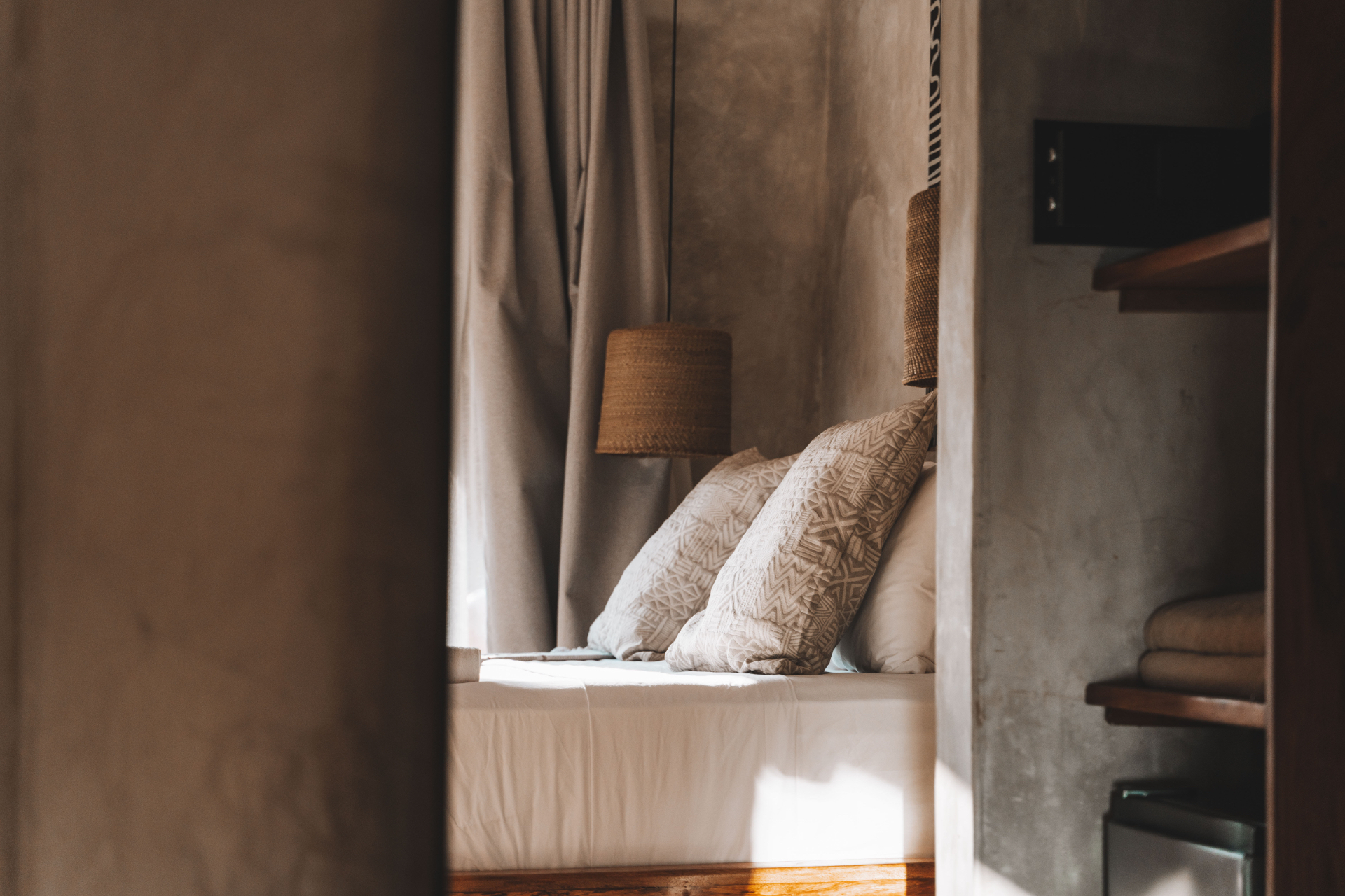 Bed with mud-cloth cushions seen through a plaster doorway in soft light