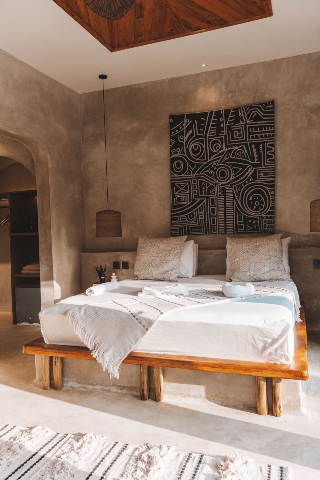 Villa bedroom with graphic African canvas, timber platform bed and plaster walls