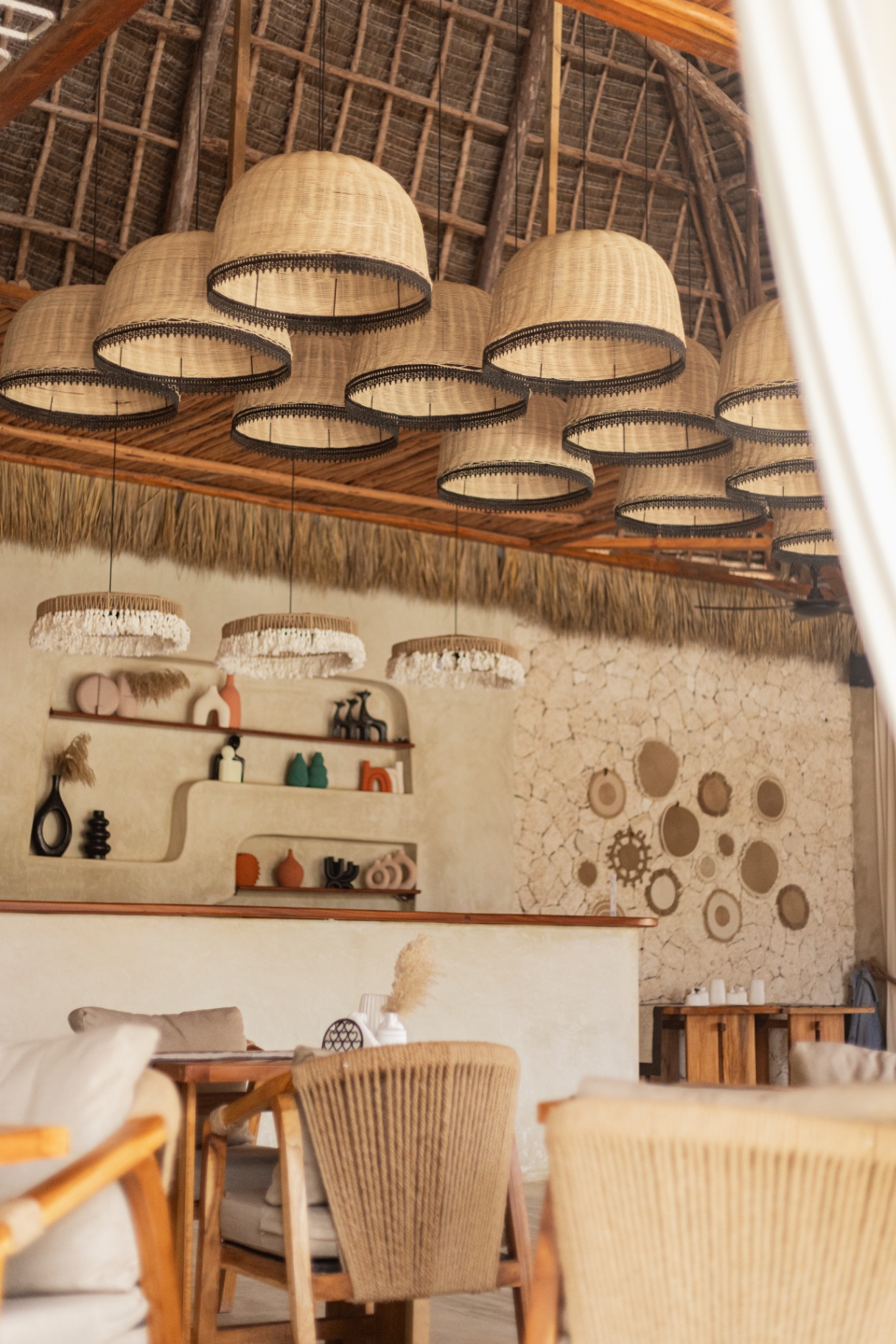 Double-height makuti roof over the lounge with clustered woven rattan pendants
