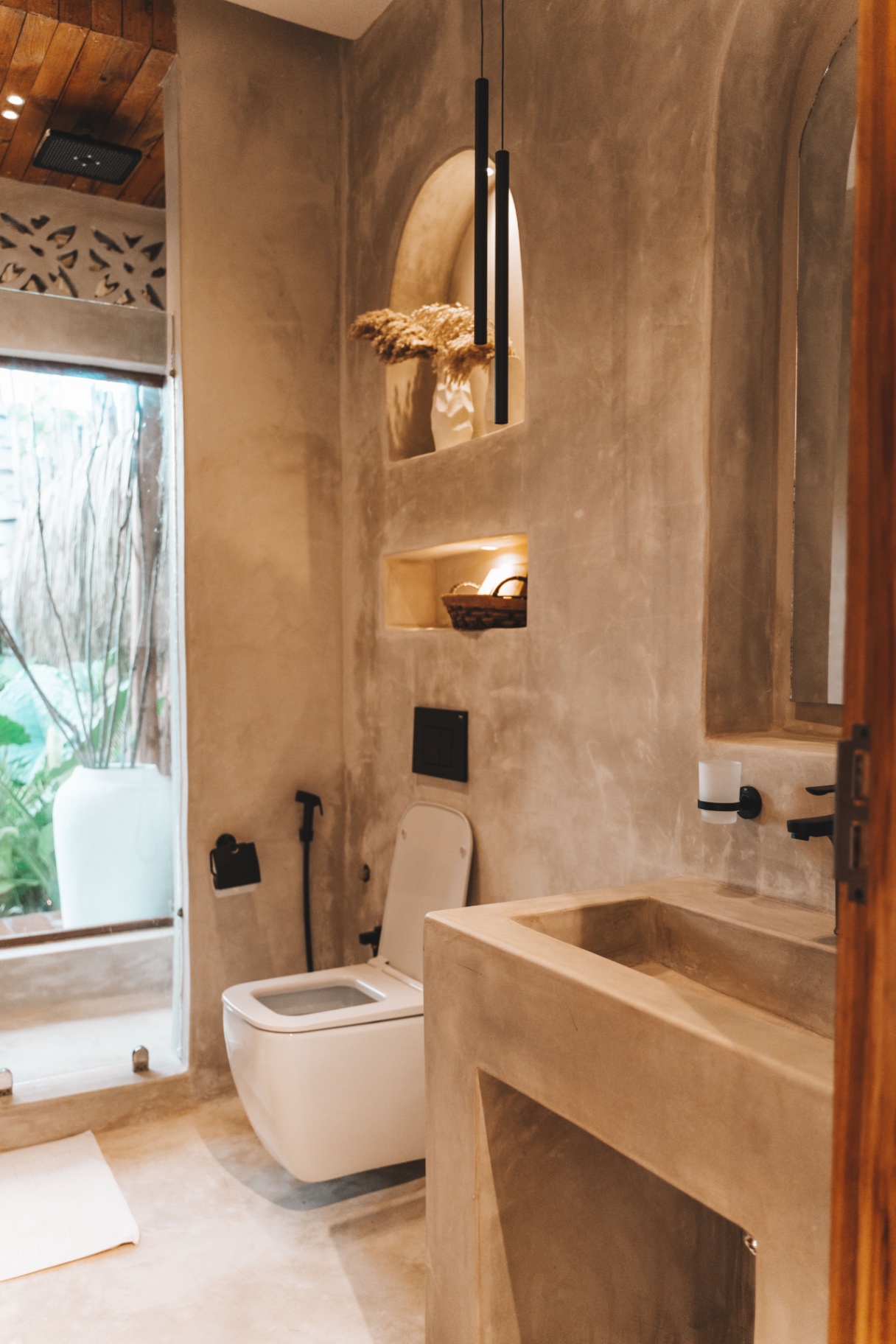 Micro-cement bathroom with slim black pendants and a garden window