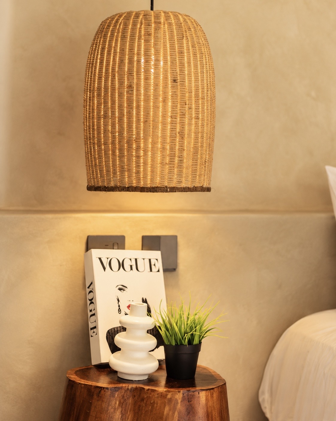Woven rattan pendant above a raw timber bedside table