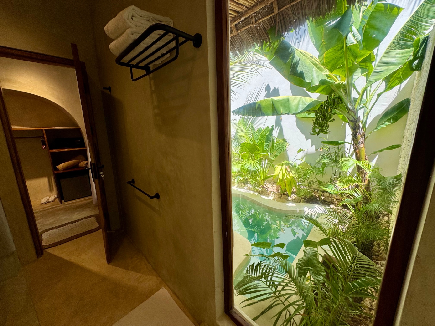 Private plunge pool and banana palms seen from the villa bathroom