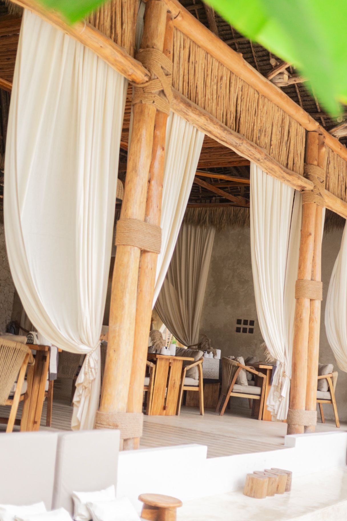 Open pavilion at Kai Zanzibar with makuti thatch roof, timber columns and linen curtains