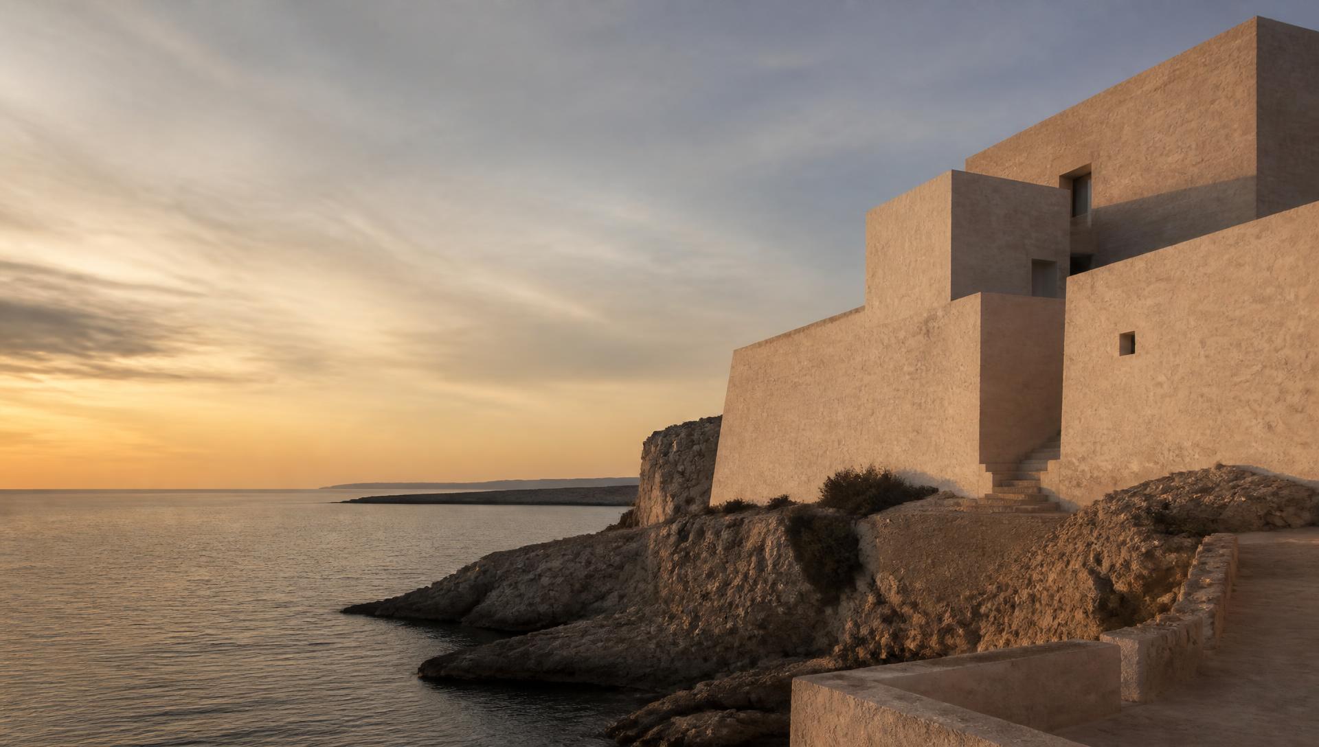 Limestone architecture meeting a rocky coastline at dusk