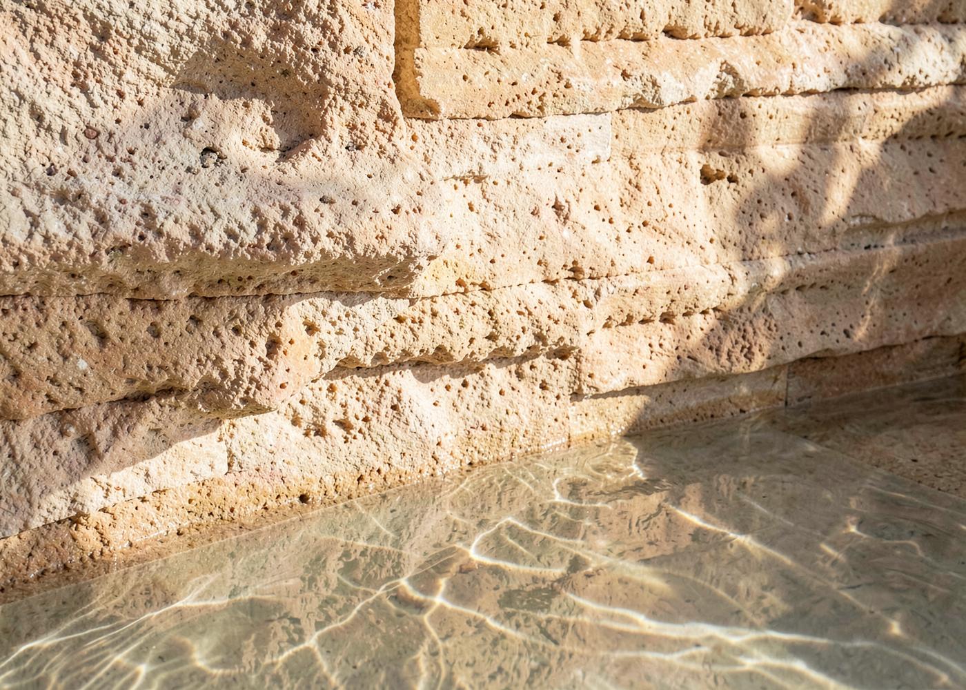 Travertine wall meeting still water with sunlight caustics